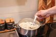 © Ina - Man cooking dumplings on the stove, adding spices and stirring, teamwork and male participation in household tasks. A warm and authentic family cooking together at home. Real domestic life.