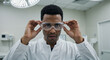 © Tamaras Pictures 4U - Black male doctor adjusting safety glasses in a medical setting