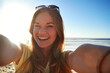 © ReeseArcurs/peopleimages.com - Face, girl and happy with selfie on beach for travel adventure, holiday memory and profile picture. Social media influencer, woman and photo at seaside for status update, online post and mockup space