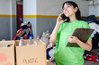 © South Pixels - Smiling young woman volunteer talking on the phone at a recycle factory.Recycle concept.Earth Day concept.