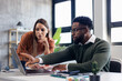 © MexChriss - Coworkers collaborating on laptop pointing at screen in office