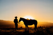 © Connect Images - Cowboy and horse silhouetted by a glowing sunset in a grassy landscape. Oregon, USA