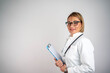 © Nenad - Happy smiling mature female doctor writing on clipboard, isolated on background.