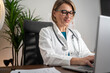 © Nenad - Joyful female doctor using notebook in clinic
