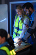 © ultramansk - A diverse engineering team, a smiling Caucasian woman in a safety vest and an Indian man, collaborates at night. They are pointing at a glowing light table, reviewing plans.