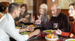 © JackF - Large friendly family gathered at table to have lunch in restaurant. Relatives eat, drink wine, and socialize. People participate in discussion during meeting.