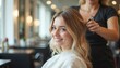 © Viktor - Young woman smiles while hairdresser styles blonde hair in beauty salon. Stylist uses comb and scissors for new haircut. Client gets makeover service in modern hair studio.