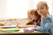 © New Africa - Happy children at desk in classroom. Space for text