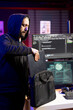 © DC Studio - Hacker in hideout putting laptop in backpack after stealing sensitive information using VPN on dark web. Man packing notebook after finishing breaking into systems to take restricted data
