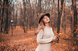 © Тамара Печеная - Young woman enjoying a serene moment in a fall forest with orange leaves on the ground
