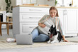 © Pixel-Shot - Young pregnant woman with cute Border Collie dog and laptop sitting on floor at home