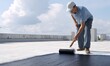 © simba kim - a man applying roof sealing with a paint roller on a flat rooftop