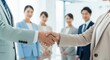 © Chainarong - Diverse group of professionals engaging in a handshake gesture, symbolizing partnership and cooperation in a modern office setting from a close-up viewpoint.
