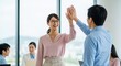© Chainarong - Two enthusiastic business professionals celebrate a successful project with a high-five in a vibrant modern office environment, symbolizing teamwork and achievement