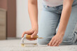 © Pixel-Shot - Young woman cleaning carpet with brush at home, closeup