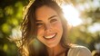 © mila103 - A young woman with long hair smiles brightly in a sunny outdoor setting. The sunlight creates a warm glow around her highlighting her joyful expression and the greenery in the background.
