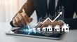 © Nasim - Tablet Displaying Real Estate Growth Chart with Houses and Arrow