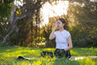 © leungchopan - Young woman doing pranayama breathing exercise outside