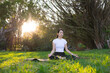 © leungchopan - Woman practicing peaceful meditation on grass outdoors