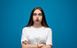 © Volodymyr_sh - Expressive young woman posing with a confused facial expression against a bright blue studio background