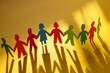 © Song_about_summer - Community, paper humans holding hands together, Diversity and Inclusion concept on yellow background. United different people standing together.