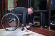 © Alex - A man in a wheelchair leaned over and prepared to turn on a CD player.