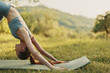 © SHOTPRIME STUDIO - Young woman practicing yoga outdoors in nature, showcasing a downward dog pose, wearing a light blue sports outfit, with a serene expression on a sunny day