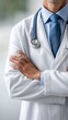 © olga_demina - Medical professional standing with arms crossed, wearing a white lab coat, blue shirt, and tie, carrying a stethoscope over the shoulders, representing healthcare and expertise
