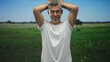 © Krakenimages.com - Man with hands behind head in grassy meadow wearing white tshirt showing raised arms and visible forearms; calm reflection.