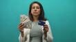 © Krakenimages.com - Woman holding a fan of banknotes and a creditcard with visible hands in studio; financial confidence.
