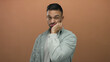 © Krakenimages.com - Young man with a playful facial expression standing against an orange background, depicting a humorous and laid-back mood.