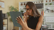 © Krakenimages.com - Thai woman wearing glasses holding a tablet folio and touching chin with finger while reading papers at desk in office building; contemplation focus.