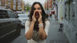 © Krakenimages.com - Woman cupping hands to mouth calling on a busy city street wearing white watch and braided bracelets, smiling with open mouth; joy announcement.