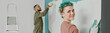 © AnnaStills - Website banner of Caucasian woman smiling at camera while painting wall with roller, young adult man in background painting wall during home renovation and moving process