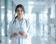 © Zulha - Smiling doctor with stethoscope and tablet in a bright hospital hallway