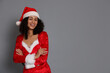 © New Africa - Beautiful woman in Mrs Claus costume on gray background, space for text. Christmas season