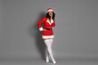 © New Africa - Beautiful woman in Mrs Claus costume on gray background. Christmas season