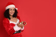© New Africa - Beautiful woman in Mrs Claus costume with baubles on red background, space for text. Christmas season