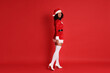 © New Africa - Beautiful woman in Mrs Claus costume on red background. Christmas season