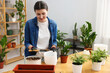 © New Africa - Transplanting houseplant. woman putting soil into pot at wooden table. Space for text