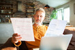 © Geber86 - Mature man reviewing bills with laptop at home, focused