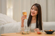 © buritora - Young Asian woman having a drink in her bedroom at home (beer, home drinking, drinking habits)