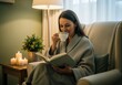 © Meow Creations - Woman in bathrobe reading book and drinking tea in cozy armchair