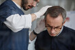 © Seventyfour - Middle aged Caucasian man being examined by young adult male dermatologist wearing gloves, doctor carefully inspecting scalp of patient during dermatology appointment