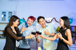 © Nuttapong punna - Happy young friends raise red wine glasses in a cozy indoor party setting, laughing and enjoying a festive dinner with good food, warmth, and positive vibes.