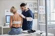 © Seventyfour - Caucasian middle aged woman sitting on examination table being examined by young male dermatologist using dermatoscope during skin check in medical office