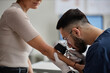 © Seventyfour - Caucasian middle aged woman undergoing skin examination by young adult Middle Eastern male dermatologist using dermatoscope, dermatologist wearing gloves and closely inspecting patient arm
