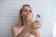 © leroy - Young woman is using mobile phone, she looks surprised and shocked by unbelievable news she received via social media