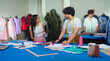 © Raushan_films - Indian young adult gen z female male man wear tape around neck use tab look screen talk share idea class room place. Tailor girl boy hold pencil do work learn cloth craft create dress pattern on paper