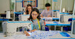 © Raushan_films - Indian young adult pupil gen z woman wear glasses tape around neck sitting class room learn new casual course good sewing machine. focused teen female girl do self craft skill indoor day college place